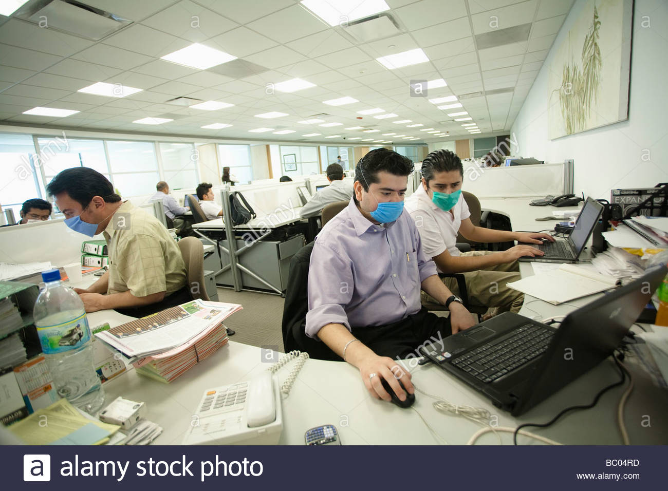 some-people-work-at-their-computers-wearing-masks-inside-an-office-BC04RD.jpg